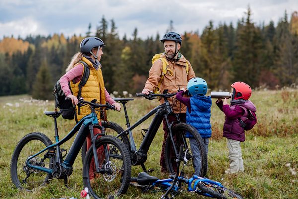 Voici une famille qui fait une balade a vélo a coté d'une foret.